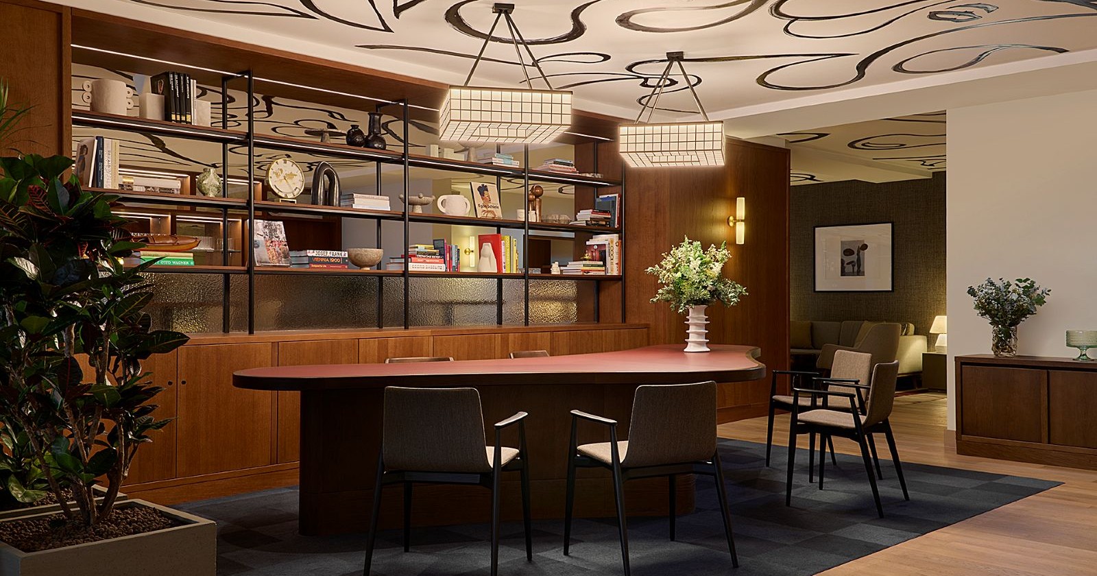 brauner Tisch, Bücherregal und Pflanzen in einer Hotellobby