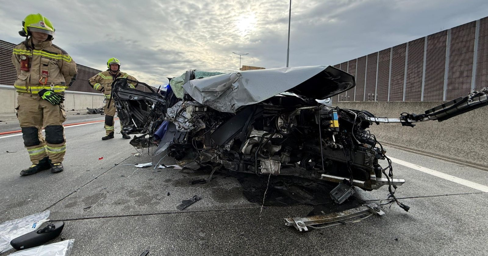 Ein völlig zerstörtes Auto steht nach einem schweren Verkehrsunfall auf der S1 bei Korneuburg auf der Fahrbahn, während Feuerwehrkräfte die Unfallstelle sichern.