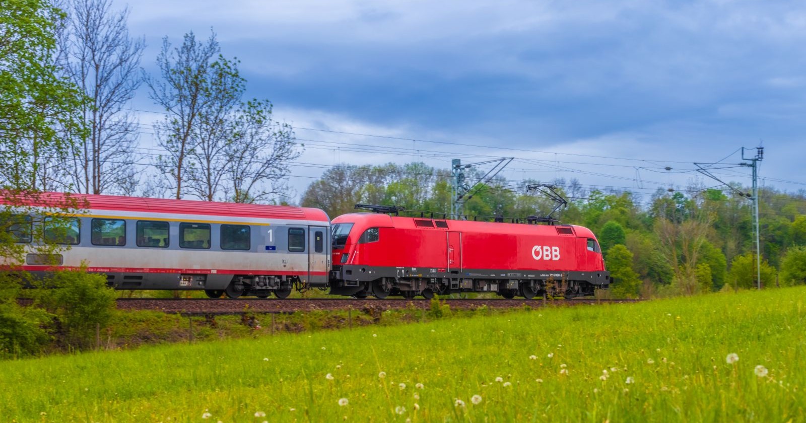 Ein Zug der ÖBB fährt durch eine grüne Landschaft in der Steiermark.