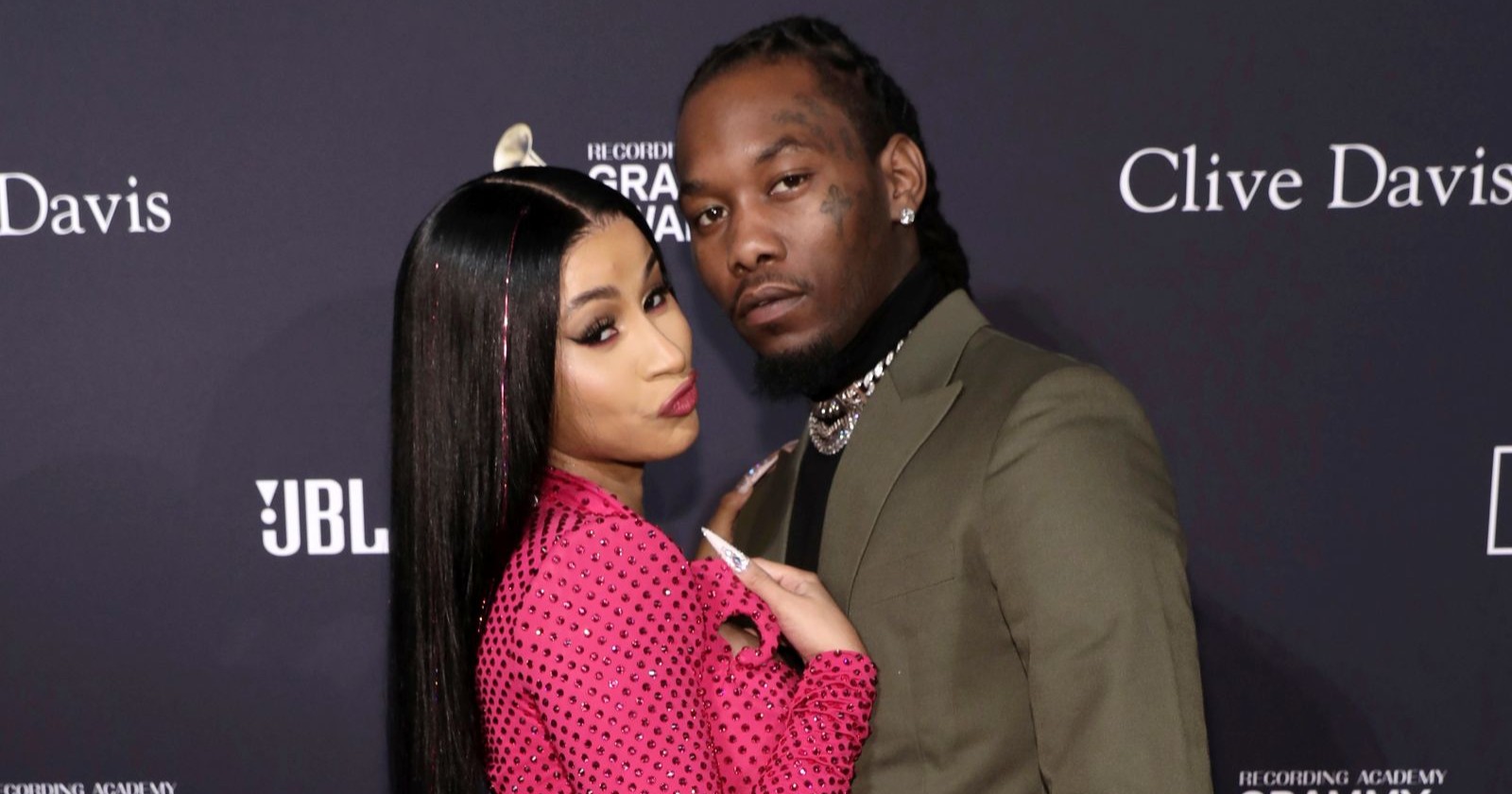 Offset und Cardi B. posieren gemeinsam auf einem Event vor einer dunklen Fotowand, beide blicken in die Kamera./ Offset wurde angeschossen