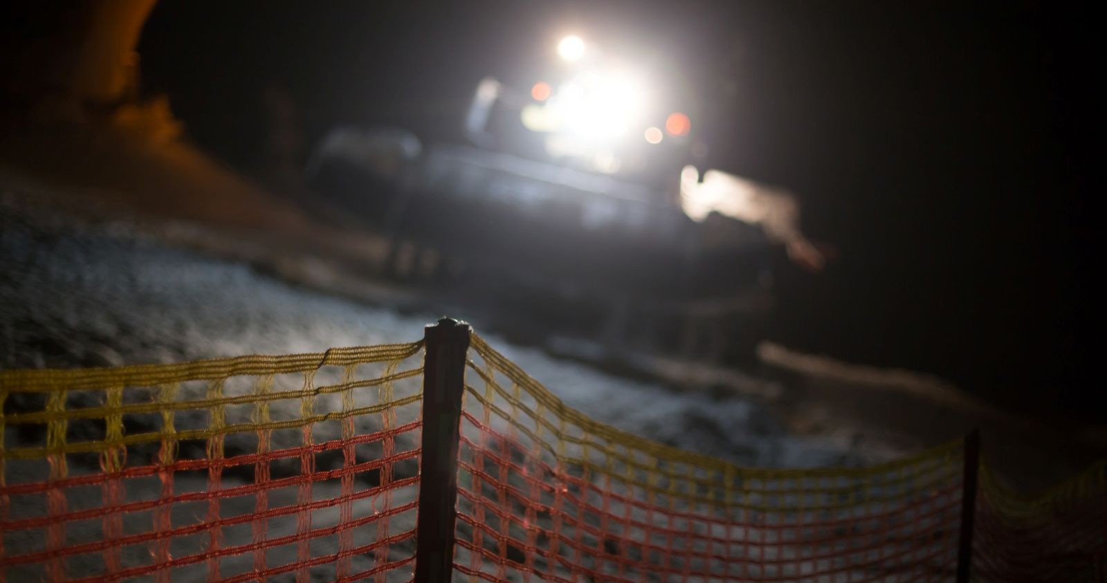 Eine Pistenraupe nachts auf der Skipiste.