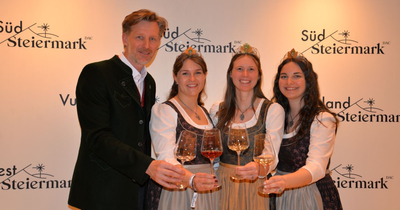 Ein Mann und drei Frauen stoßen mit einem Weinglas an