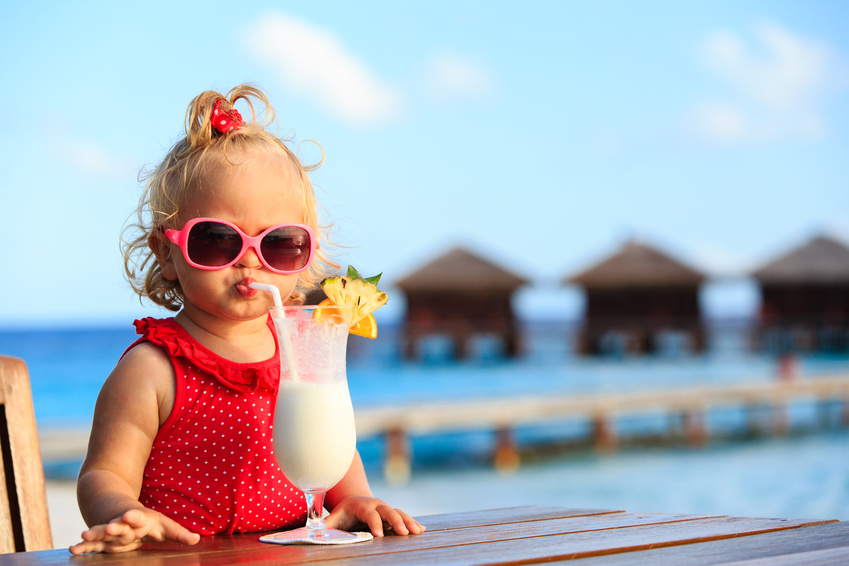 cute little girl drinking cocktail on tropical beach