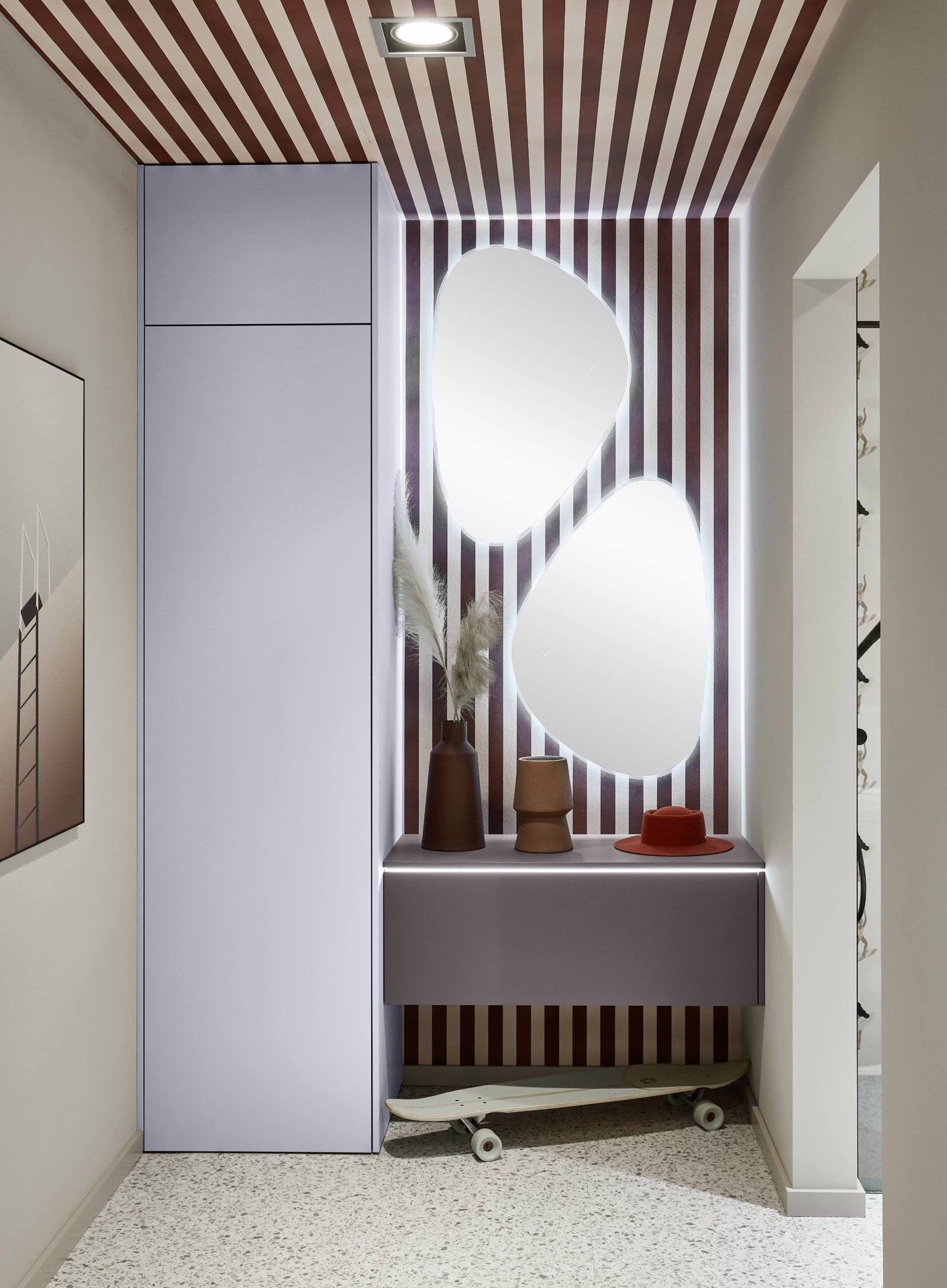 Flur mit hellviolettem grifflosem Hochschrank bis zur Decke, daneben ein hängendes Sideboard und zwei beleuchtete Spiegel vor Streifentapete, Nobilia Senso
