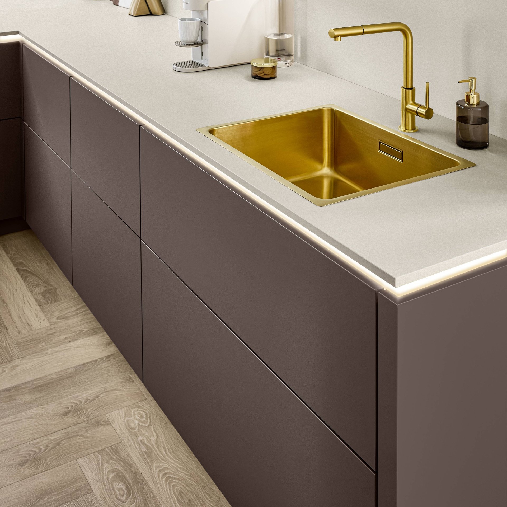 Mauvefarbene grifflose Unterschränke mit beleuchteter Griffmulde unter heller Arbeitsplatte, goldfarbene Einbauspüle und Armatur, Nobilia Line N Senso