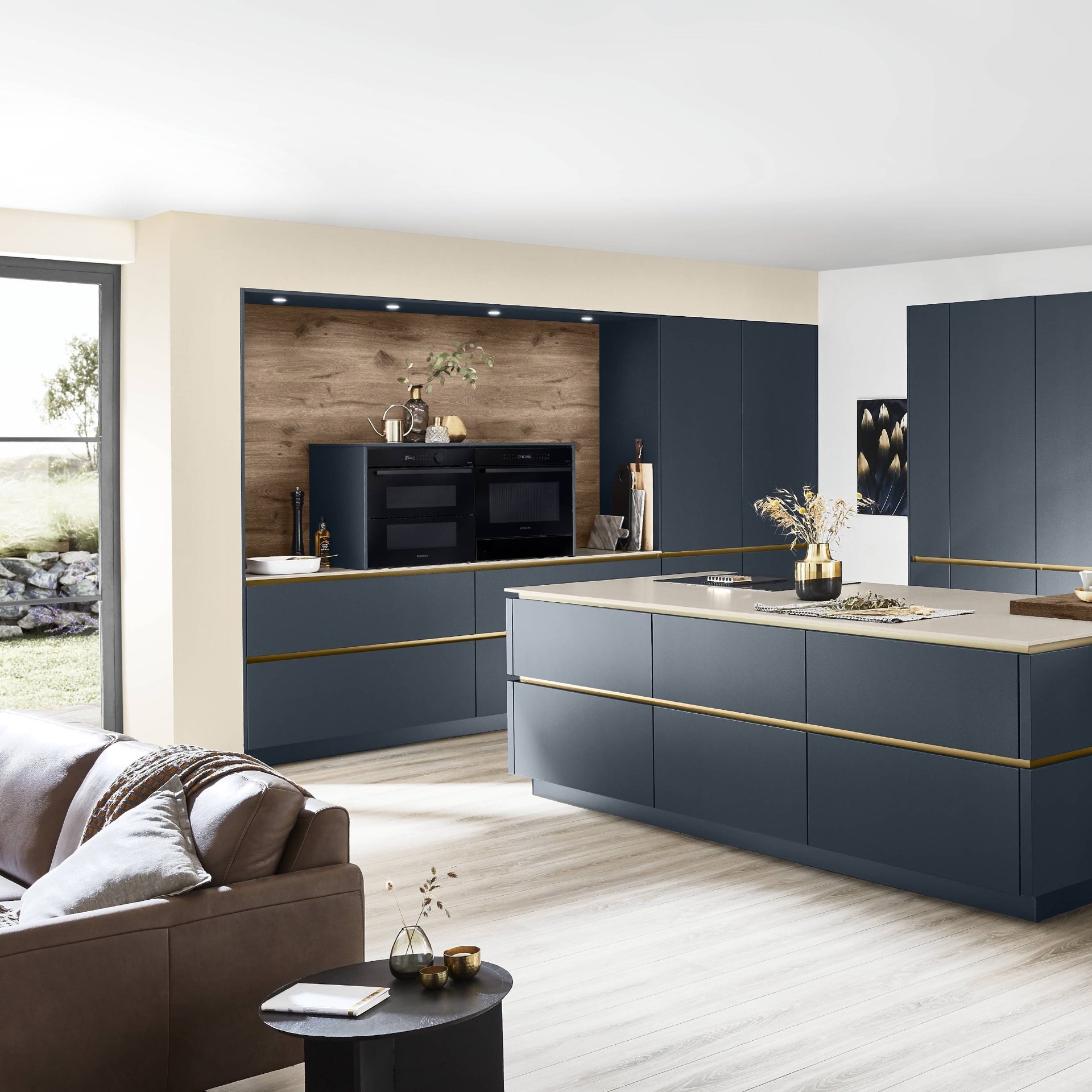 Dunkelblaue grifflose Küche mit goldfarbenen Griffmulden, zwei Einbaubacköfen übereinander in einer Holznische und Kücheninsel, Nobilia Line N Easytouch