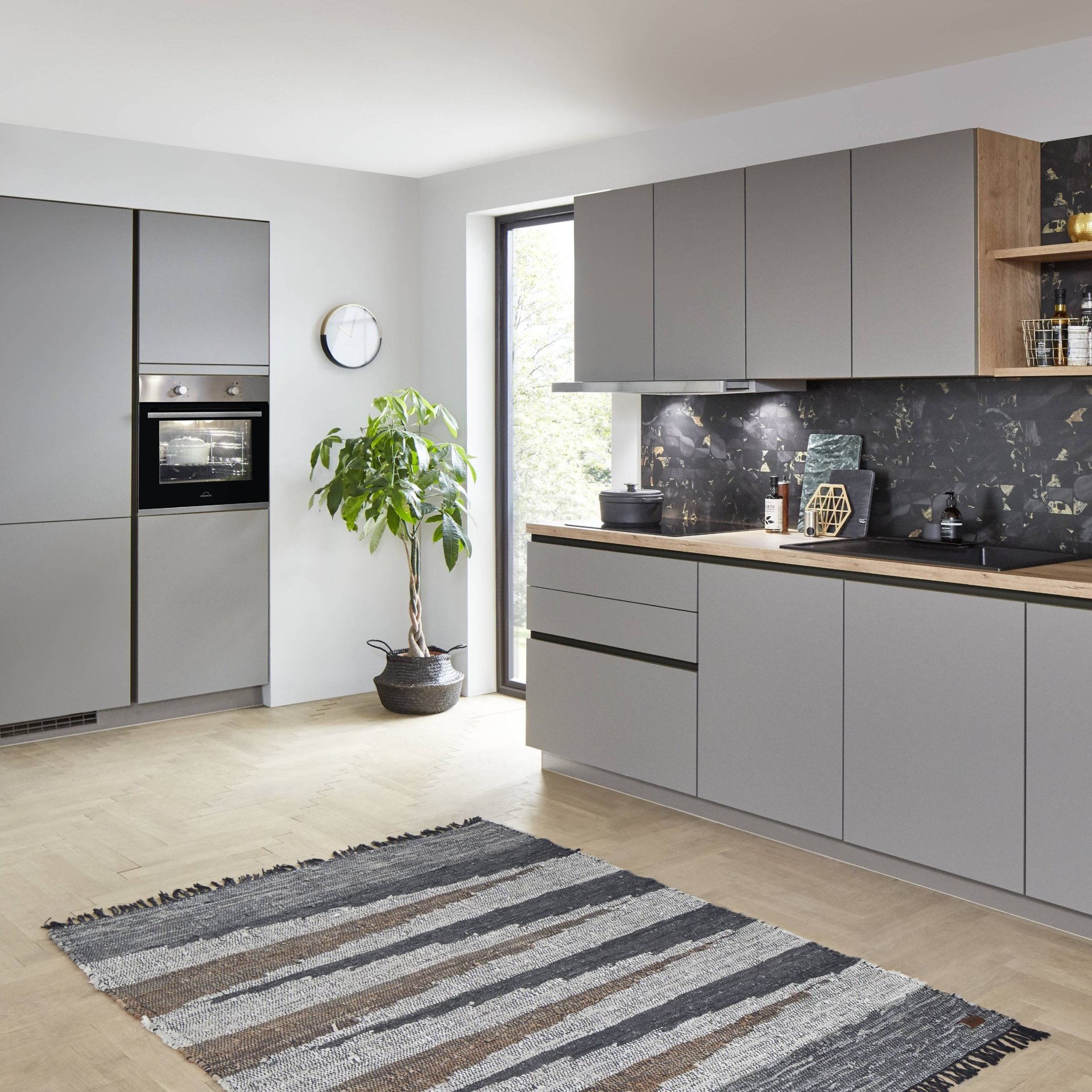 Graue grifflose Küchenzeile mit Hochschrank und Einbaubackofen links, daneben Unterschränke und Hängeschränke, Nobilia Line N Easytouch