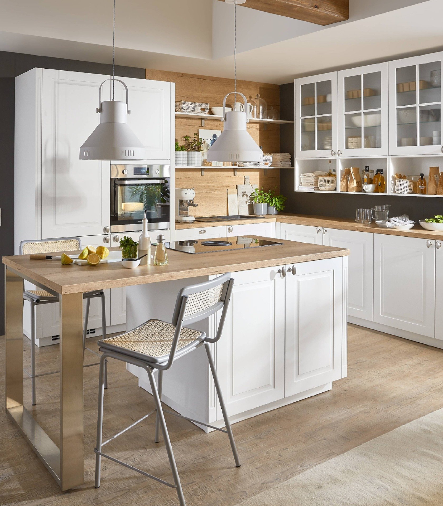 Weiße Landhausküche mit Kücheninsel, Rahmentüren mit Knöpfen und Holzarbeitsplatte, dahinter Glas-Hängeschränke
